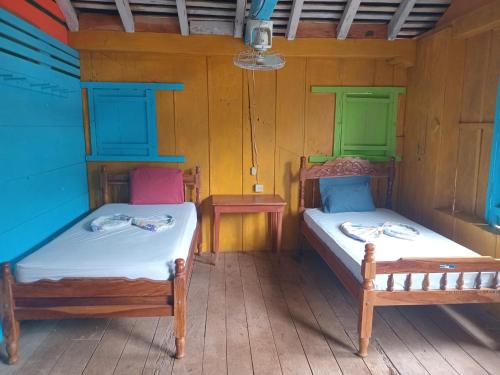 two beds in a room with wooden walls at Eco lodge finca magdalena in Altagracia