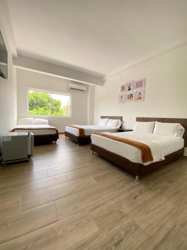two beds in a room with wooden floors at Hotel FENIX in Doradal