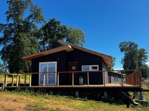 a house with a wrap around deck on a field at Antu relajo y natura in Curacautín