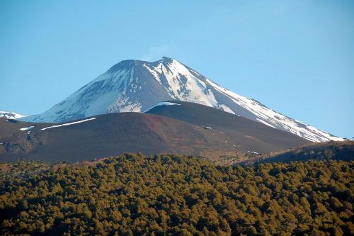 a snow capped mountain with trees in front of it at Antu relajo y natura in Curacautín