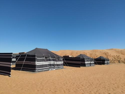 a row of black tents in the desert at Desert Hills Oman Bidiyah Camp in Bidiyah