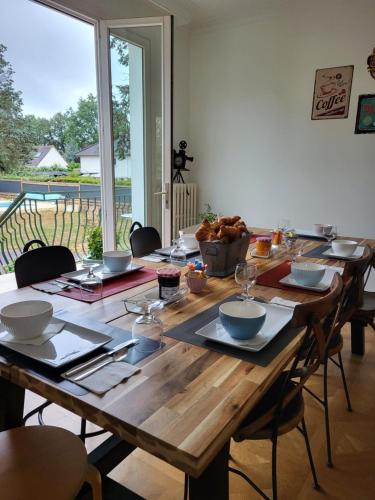 une table en bois avec des bols et des assiettes au-dessus dans l'établissement La Bodéga, à Arnage