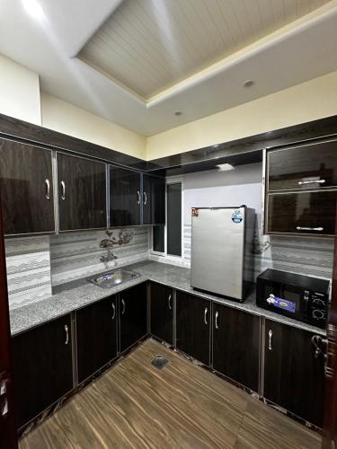 a kitchen with black cabinets and a white refrigerator at Elite Guest Rooms Apartments in Gujrānwāla
