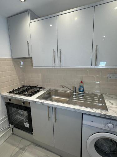 a kitchen with a sink and a washing machine at Two Bedrooms Bungalow Garden Lodge in Aveley