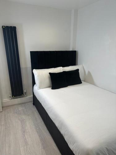 a bed with a black headboard and white pillows at Two Bedrooms Bungalow Garden Lodge in Aveley