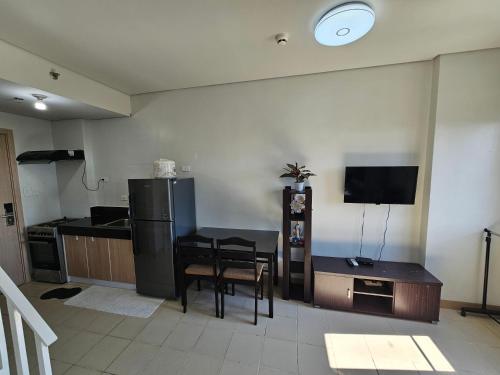 a kitchen with a table and a refrigerator and a television at B&C Staycation by SMDC Cheer Residence in Lias