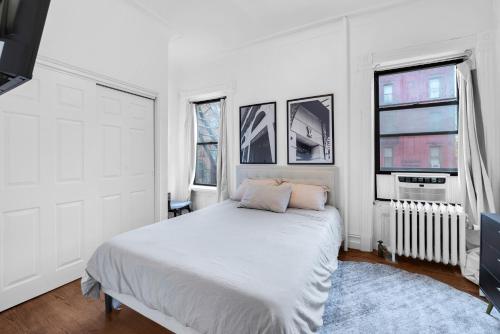 a white bedroom with a bed and two windows at Stylish 3Bd Heart of Park Slope in Brooklyn