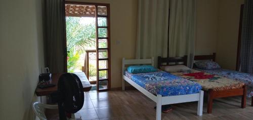 a bedroom with two beds and a door to a patio at CHALÉ LUZIMAREs 01 in Ilhéus