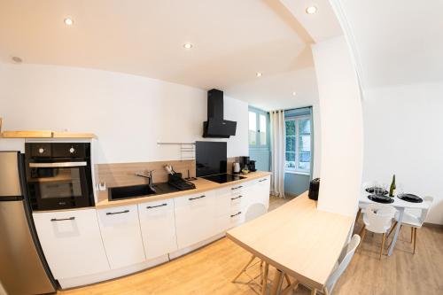 une cuisine avec des armoires blanches et une table en bois dans l'établissement Les Mouettes - Centre Ville - à 500m du Port, à Granville