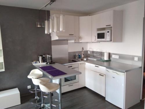 une cuisine avec des armoires blanches et un comptoir avec des tabourets dans l'établissement Le41Annecy T2 40m2 old town private parking, à Annecy