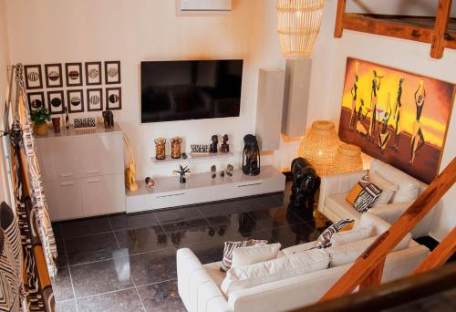 a living room with two white couches and a flat screen tv at Kimbo do Soba Resort in Sá da Bandeira
