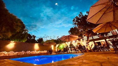 a swimming pool with chairs and umbrellas at night at Pousada Flor de Pequi in Serra do Cipo