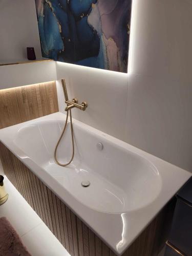 a white sink in a bathroom with a painting on the wall at Apartament Cień Wiatru z Widokiem na Jezioro i Netflixem in Charzykowy