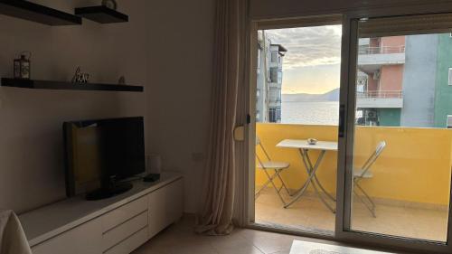 a living room with a television and a view of a balcony at Christina's Apartment in Vlorë