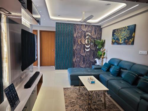 a living room with a blue couch and a tv at Evara - Premium Fully AC - 3BHK Luxury Apartment with Style in Trivandrum