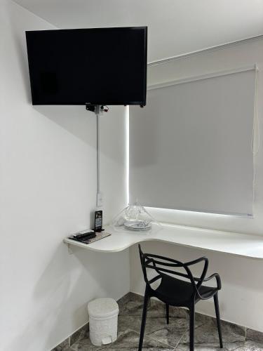 a black chair sitting in front of a desk with a television at FRAN's - HOSPEDAGENS in Lagoa Santa