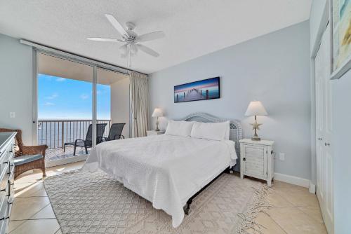 a bedroom with a white bed and a balcony at Beach Club Catalina 1407 in Gulf Highlands