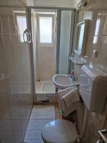 a bathroom with a shower and a toilet and a sink at Apartmani Neda in Rab