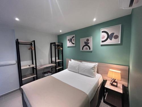 Un dormitorio con una cama blanca y una pared verde. en Hotel Sol Caribe Cartagena, en Cartagena de Indias