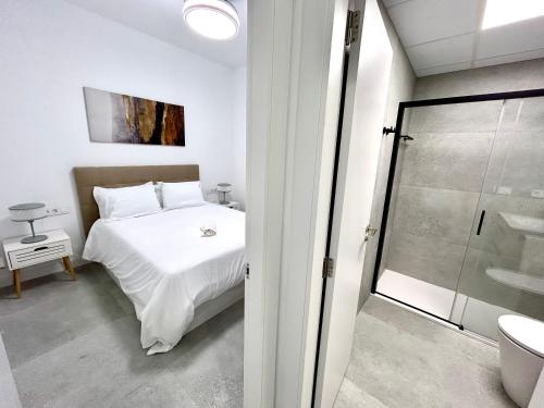 a bedroom with a white bed and a glass shower at Valencia Comfort Stay Near Metro, 2 Bed, 1 Bath in Valencia