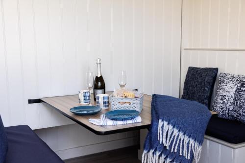 a table with two blue plates and wine glasses at Quarterlands Glamping, Shepherds hut Bracken in Crawfordsburn