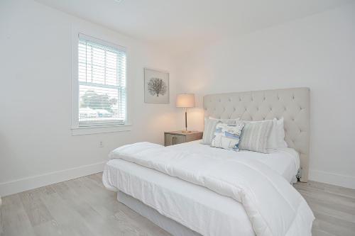 a white bedroom with a large bed and a window at Harbourtown Suites on Plymouth Harbor in Plymouth
