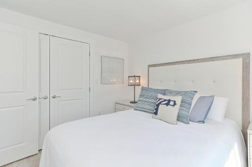 a white bedroom with a white bed with blue pillows at Harbourtown Suites on Plymouth Harbor in Plymouth