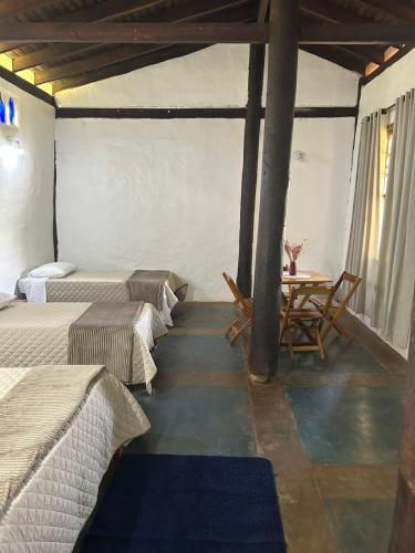a room with two beds and a table in it at Pousada Mãe Terra in Torrinha
