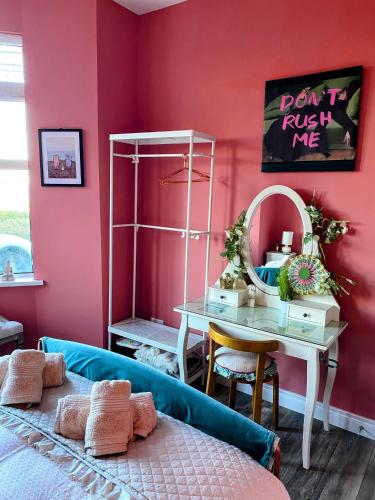 a bedroom with pink walls and a table and a bed at Port Pour Deux in Portrush
