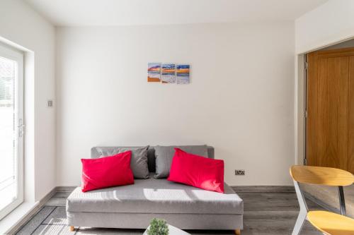 a gray couch with red pillows in a living room at A50 Apartments Stoke - 3 Bedrooms - 3 Bathrooms incl 2 ensuites house in Stoke on Trent
