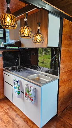 a kitchen with a stove and some lights at Hospedaje Rural Sicaru in Pacho