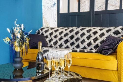 - un canapé jaune avec des verres à champagne sur une table dans l'établissement Le Baleschoux - Parking - PrestiPlace Collection, à Tours