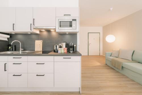 a kitchen with white cabinets and a couch in a room at 5 Min Central 1-Room Apartment - free parking 600 mbit Wifi in Bayreuth