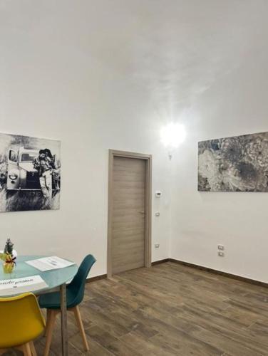 a room with a table and chairs and paintings on the wall at Appia Apartment - Camera Fiorellino in Santa Maria a Vico
