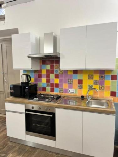 a kitchen with white cabinets and a stove top oven at Appia Apartment - Camera Fiorellino in Santa Maria a Vico