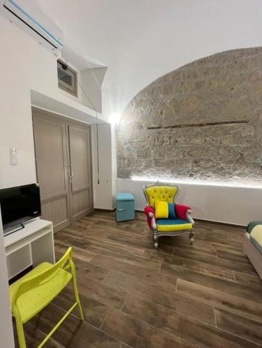 a living room with yellow chairs and a stone wall at Appia Apartment - Camera Fiorellino in Santa Maria a Vico