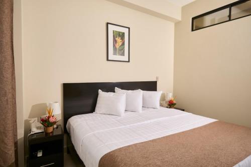 a bedroom with a large bed with white sheets at Hotel Marañón in Iquitos