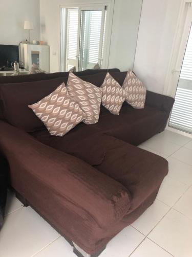 a brown couch with four pillows on it at Silent coast apartment in Las Galletas