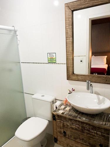 a bathroom with a toilet and a sink and a mirror at Eco Hotel Bouganville in São José dos Pinhais
