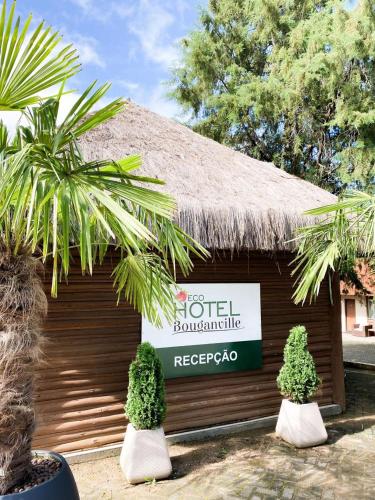 a sign on a building with two plants in front of it at Eco Hotel Bouganville in São José dos Pinhais