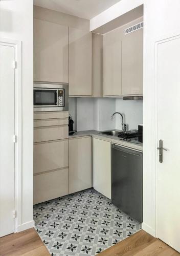 a kitchen with white cabinets and a black and white tile floor at Studio de charme à Montrouge - 20 m² - Internet inclus in Montrouge