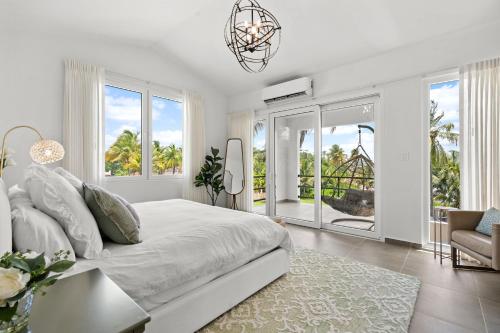 a white bedroom with a large bed and windows at Olive Villa Palmas - Modern Beachfront in Humacao