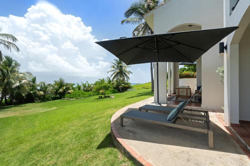 a patio with a chair and an umbrella at Olive Villa Palmas - Modern Beachfront in Humacao