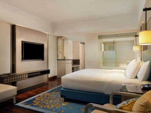 a hotel room with a large bed and a television at Hilton Bali Resort in Nusa Dua