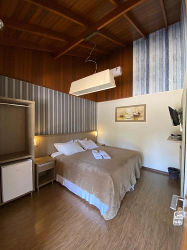 a bedroom with a bed and a flat screen tv at Eco Hotel Bouganville in São José dos Pinhais