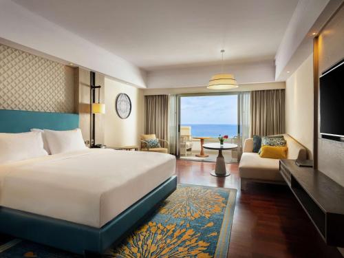 a hotel room with a bed and a living room at Hilton Bali Resort in Nusa Dua