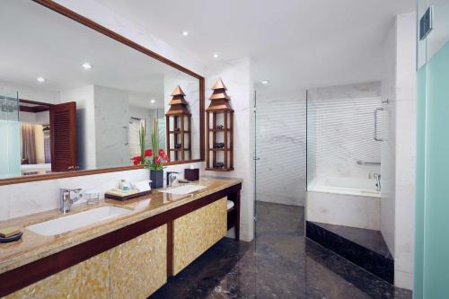 a bathroom with two sinks and a shower and a tub at Hilton Bali Resort in Nusa Dua