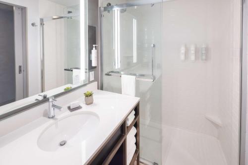 a white bathroom with a sink and a shower at Hilton Garden Inn Redmond WA in Redmond