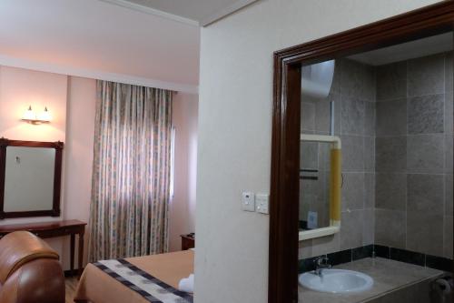 a bathroom with a sink and a bed and a mirror at Jeruton Hotel in Kampong Jerudong