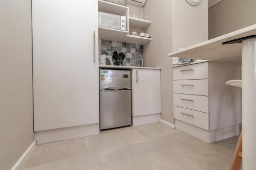 a kitchen with white cabinets and a refrigerator at Beach View Brooke's Hill Suites in Gqeberha